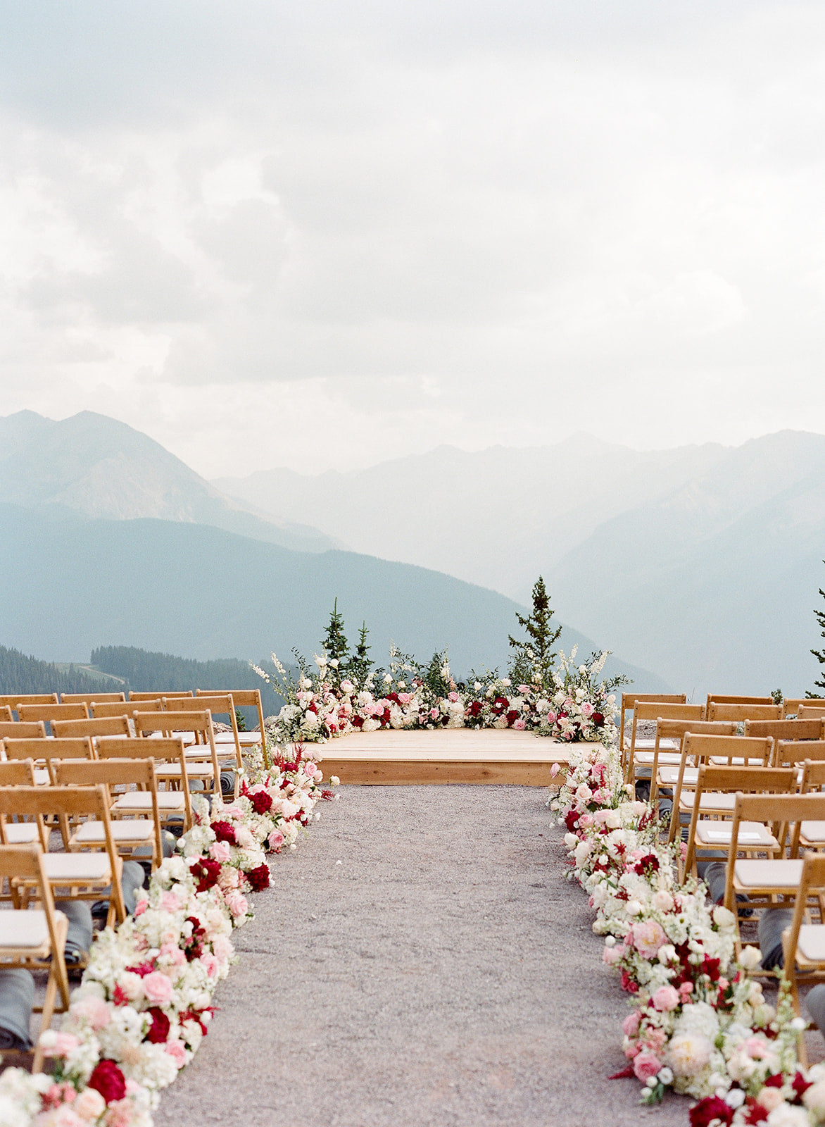 Wedding ceremony setup with floral arrangements and chairs against a mountainous background