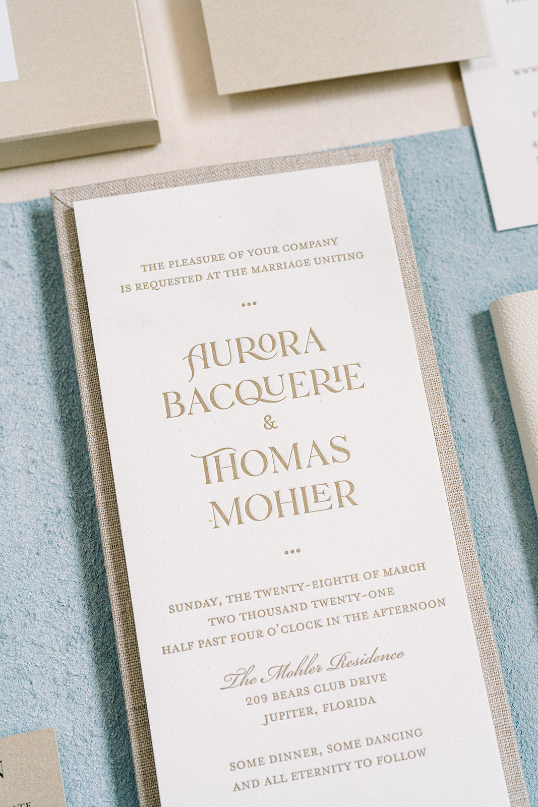 Wedding invitation card with gold text on a textured surface