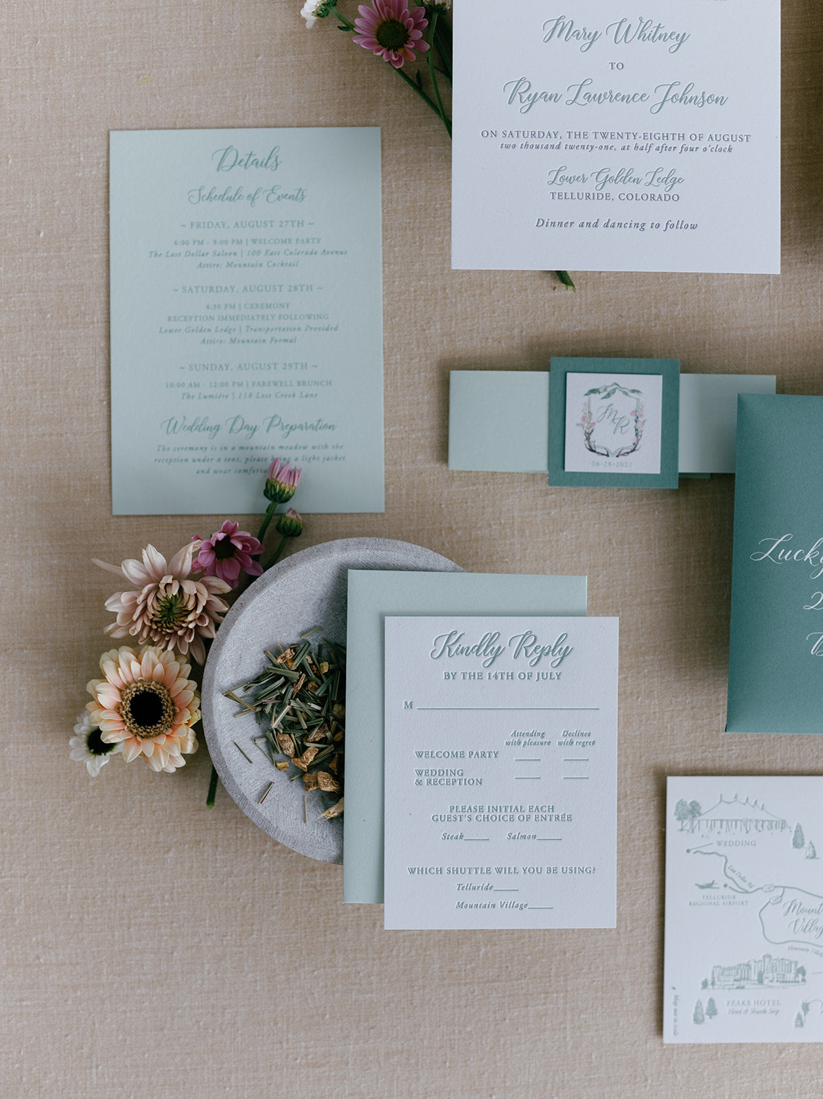 Set of wedding invitations and RSVP cards on a textured surface with flowers.